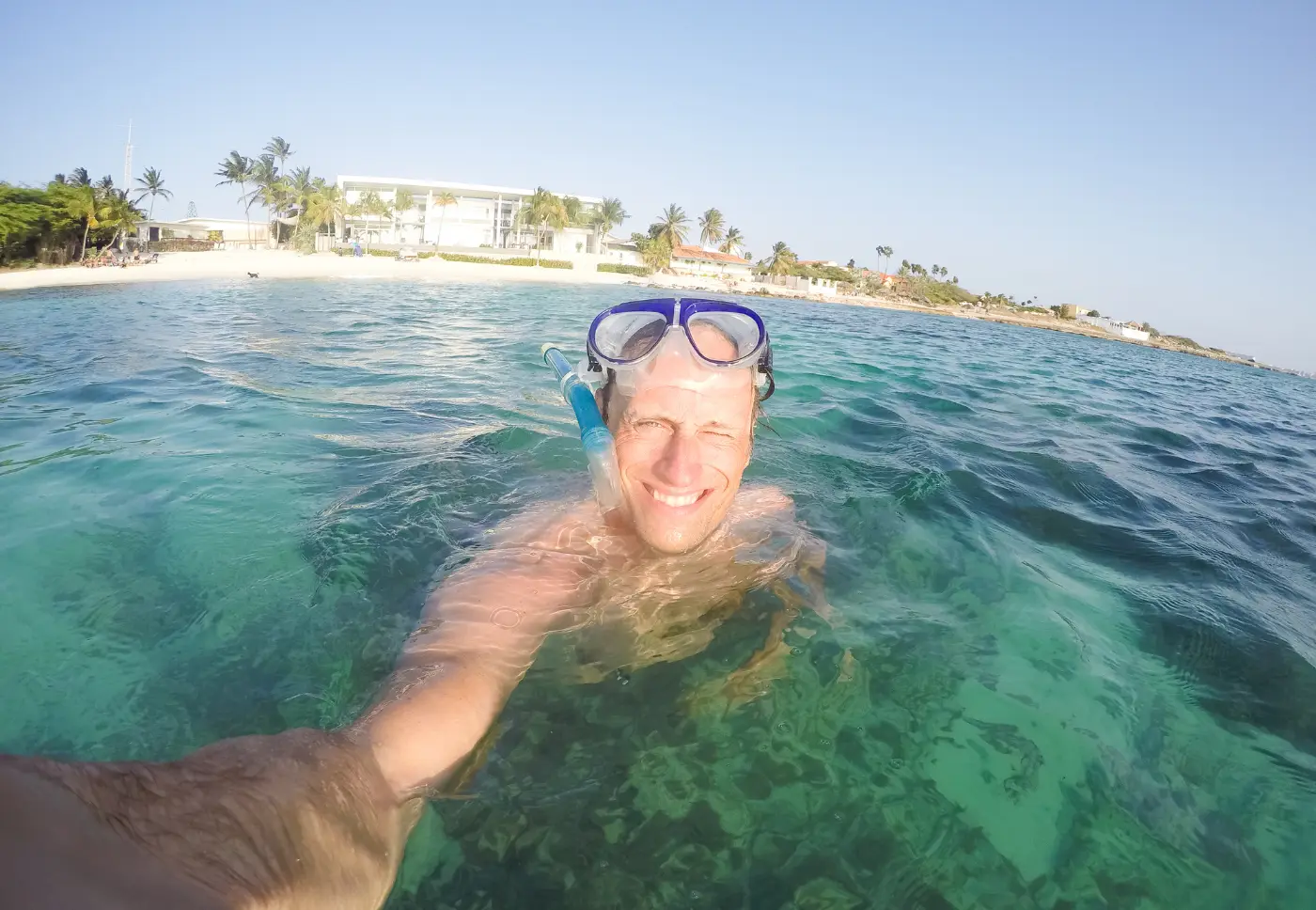 A snorkeler smiles at the camera in clear turquoise water off Aruba's coast