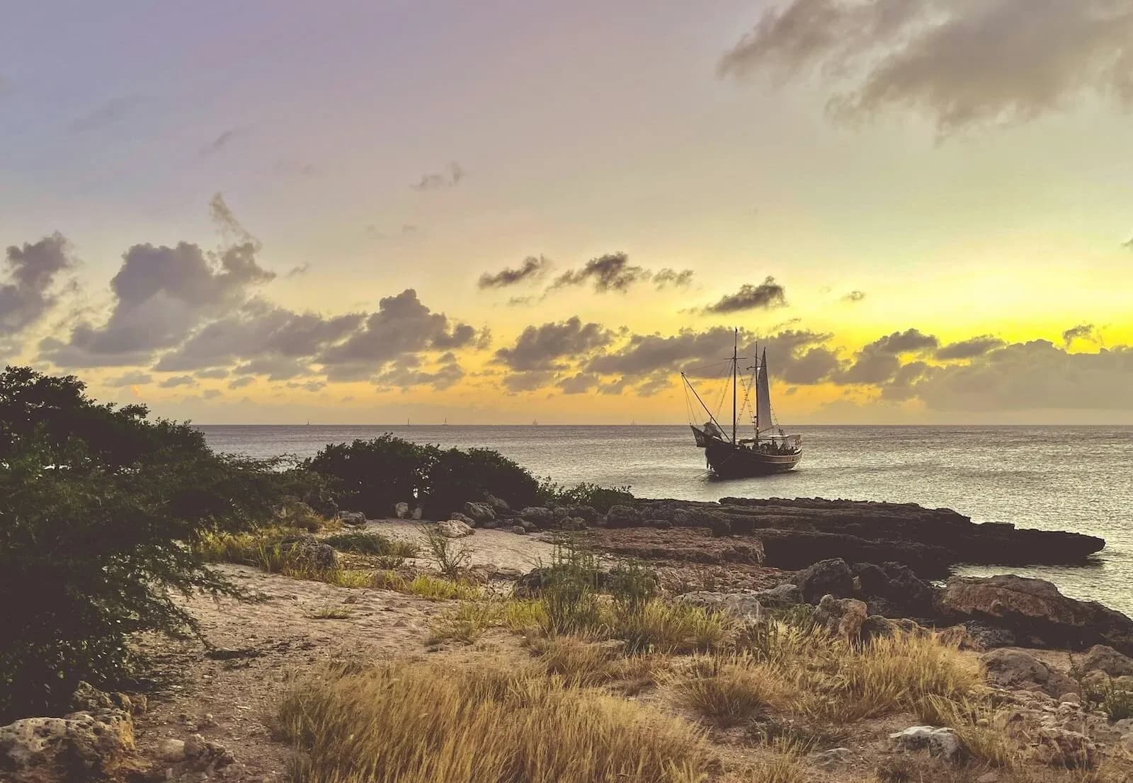 The Flagship Aruba schooner silhouetted against a sunset off Aruba's coast