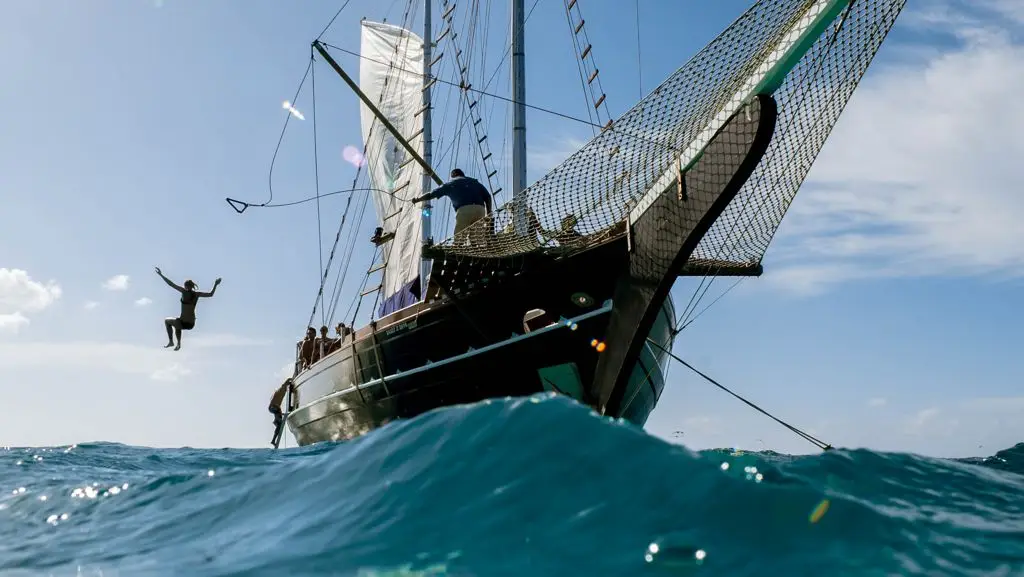 A guest jumps from the schooner into the ocean