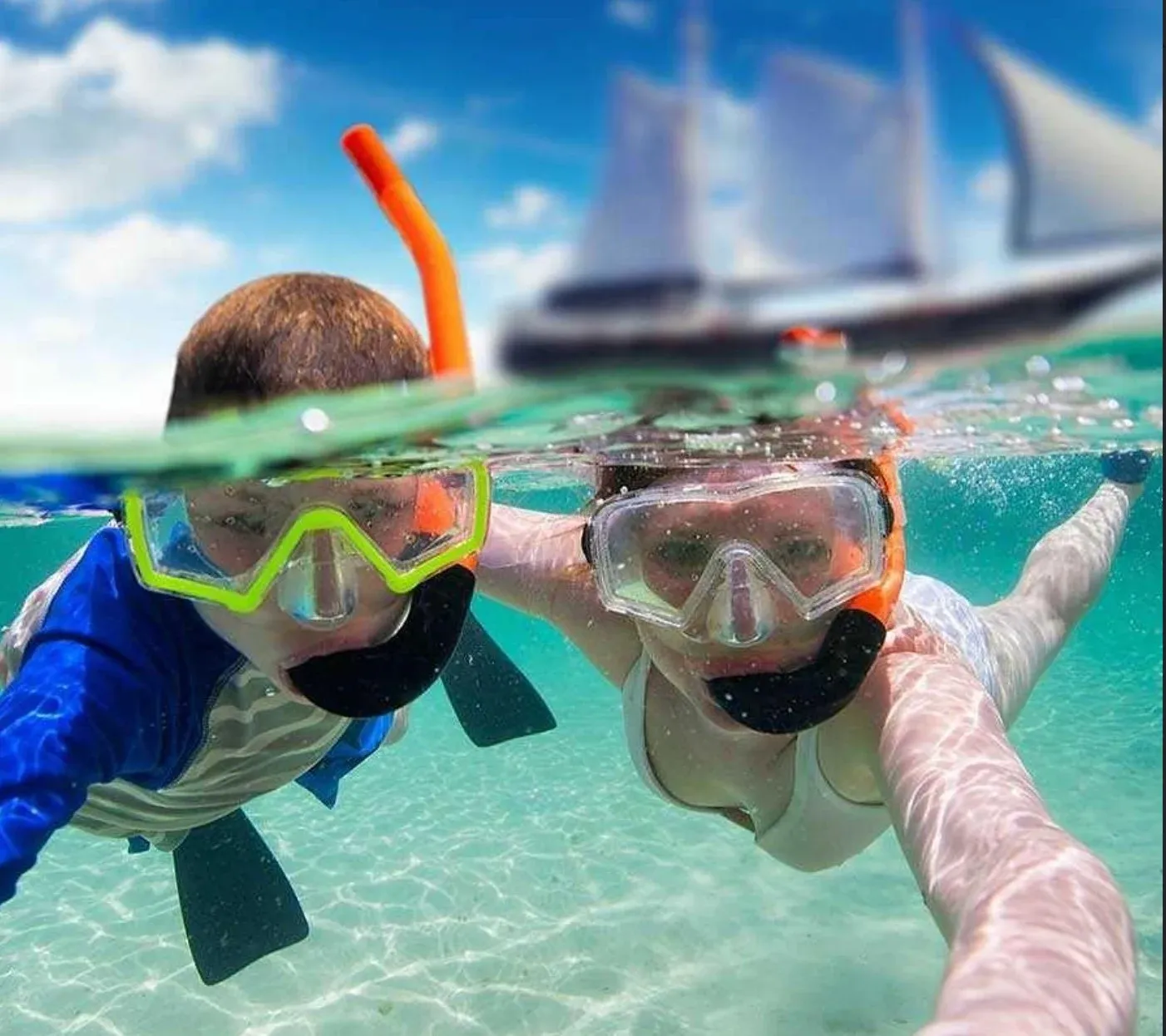 A parent and child snorkeling together with the schooner behind them